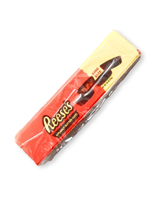 „Miękki Butter Squishy w kształcie podłużnego batonika. Pomarańczowo-brązowa kolorystyka i nadruk inspirowany słodyczami Reese’s. Zaokrąglone krawędzie, realistyczny wygląd batonika.”